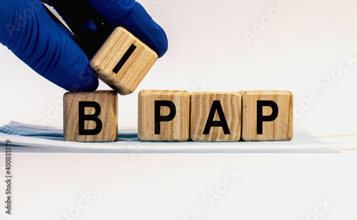 Text BIPAP made from wooden cubes. Hands in a blue glove.