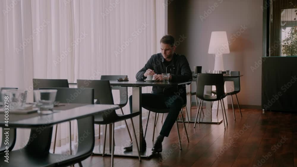 Man putting his earbuds in his ears while sitting in an empty restaurant