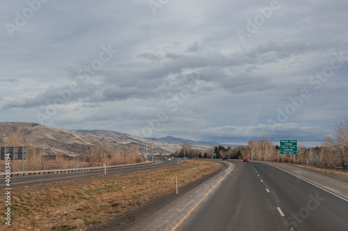 A beautiful landscape with a highway along which cars and trucks drive  on a sunny autumn day among the mountains  a blue sky with fluffy gray-blue clouds. Oregon  USA  12-5-2019