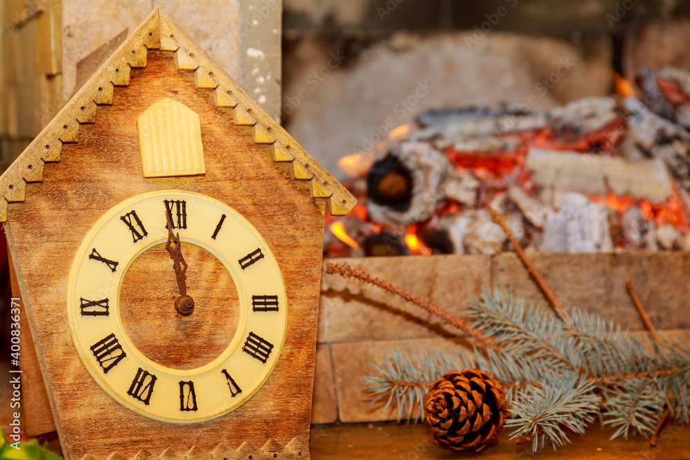 Retro clock with cuckoo with Roman numerals on the background of a fireplace with fire.