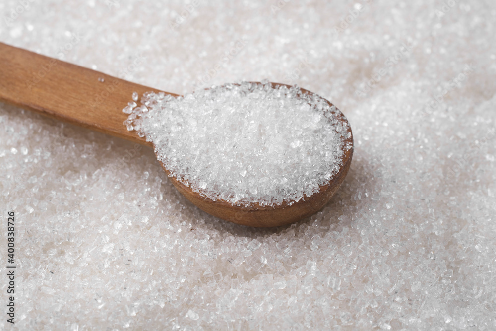 Wooden spoon with sugar on a background of sprinkled sugar. Wooden spoon with sugar on a background of sprinkled sugar.