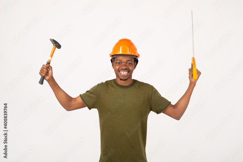 handsome young african man on white background in construction helmet with saw and hammer