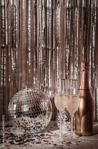 Glasses of champagne and a bottle,  a disco ball on a shining gold surface. New Years Eve party background