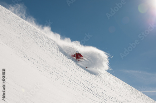 Freeride skier going fast downhill. Stock picture of a freeride skier that is skiing fast downhill in deep powder snow. There is a beautiful clear blue sky in the background. The location is Hochgurgl