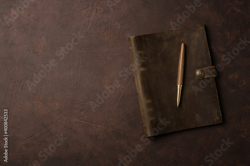 brown leather diary and pen on brown background or table