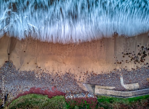 Aerial top view of sea waves hitting beach. photo