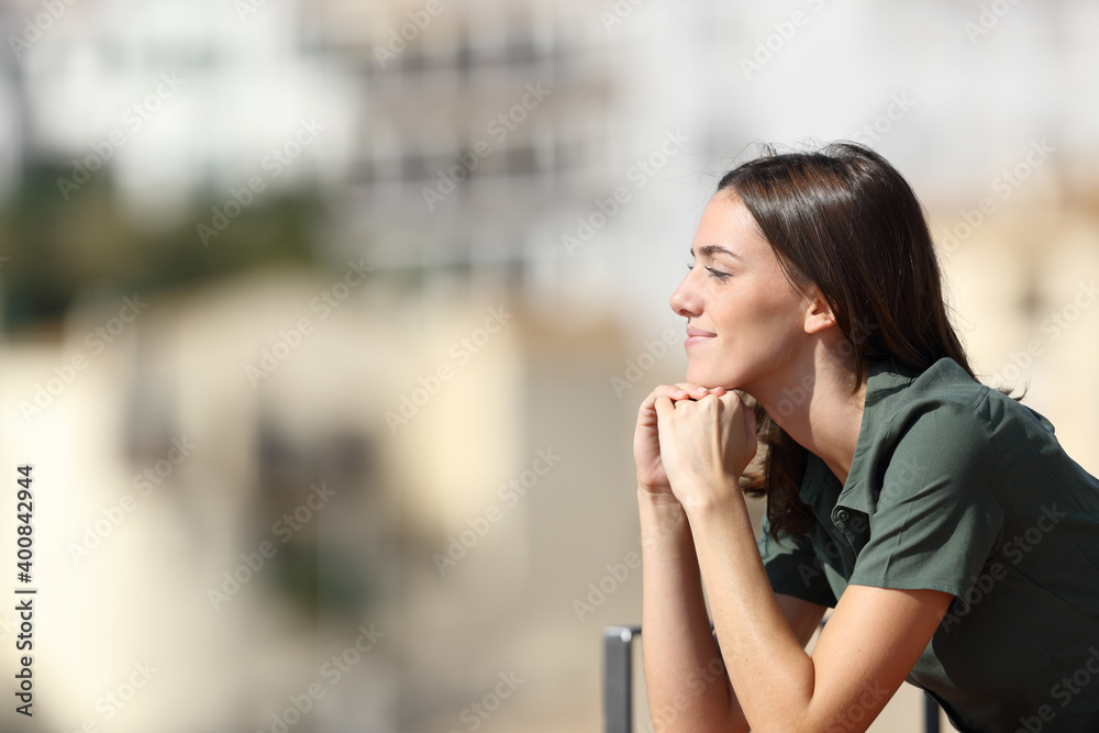 Satisfied woman contemplating from balcony in a town Satisfied woman contemplating from balcony in a town