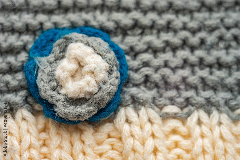 Knitted pattern of threads in two colors and styles. Small flower on a scarf.