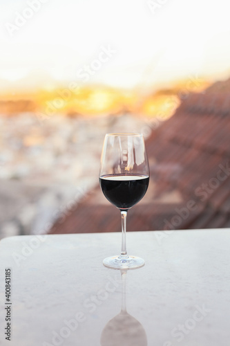 A glass of red wine on a rooftop terrace, city view on the background