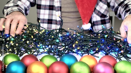 Male hands trying to prepare xmas unravel the tangled glowing lights of Decorative Christmas garland at home. photo