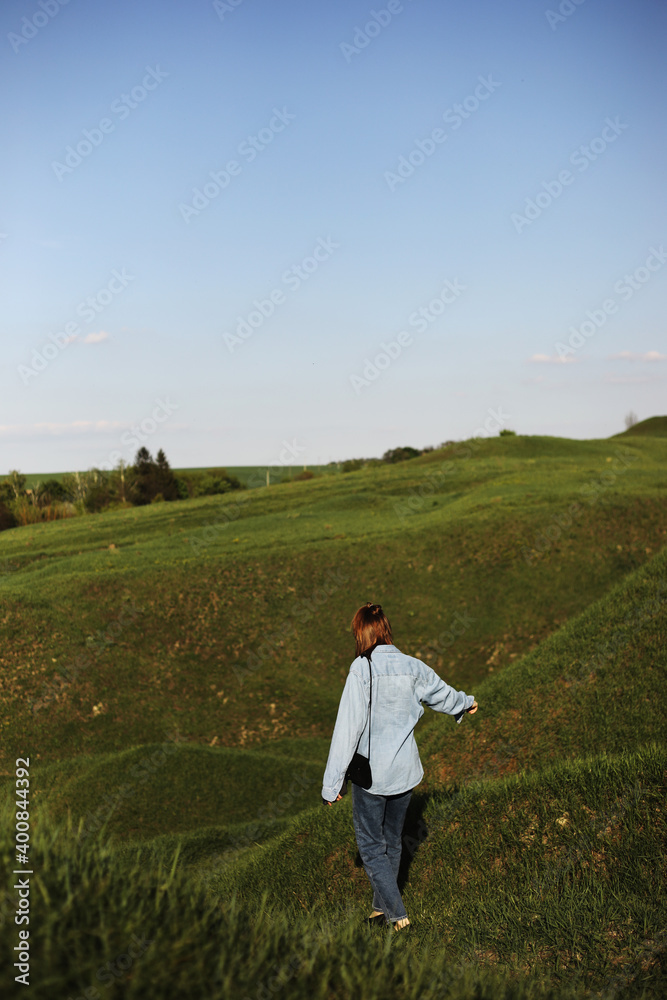 Young woman is sitting on green grass hills and feeling relax on summer sunny day