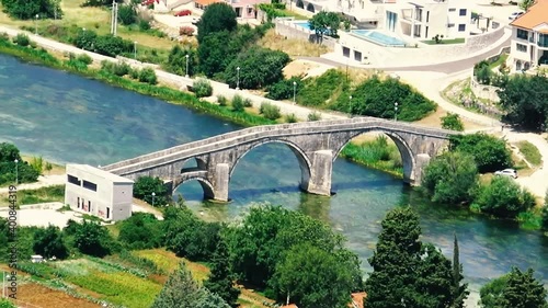 Aerial view over old stone bridge and city of Trebinje during sunny summer day.