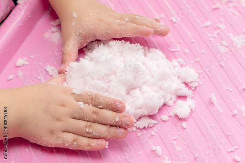 Child plays with artificial snow for home decoration