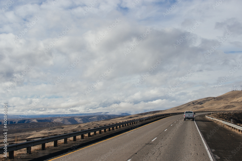A beautiful landscape with a highway along which cars and trucks drive, on a sunny autumn day among the mountains, a blue sky with fluffy gray-blue clouds. Oregon, USA, 12-5-2019 A beautiful landscape with a highway along which cars and trucks drive, on a sunny autumn day among the mountains, a blue sky with fluffy gray-blue clouds. Oregon, USA, 12-5-2019