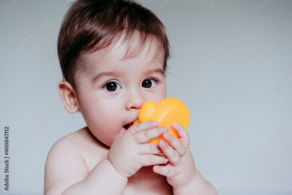 Cute little boy putting toy in his mouth while sitting at home Cute little boy putting toy in his mouth while sitting at home