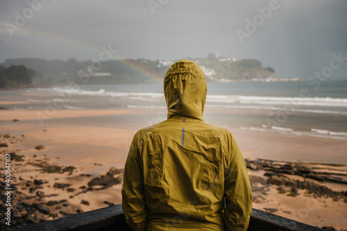 Rear view of woman wearing raincoat by retaining wall during rainy season