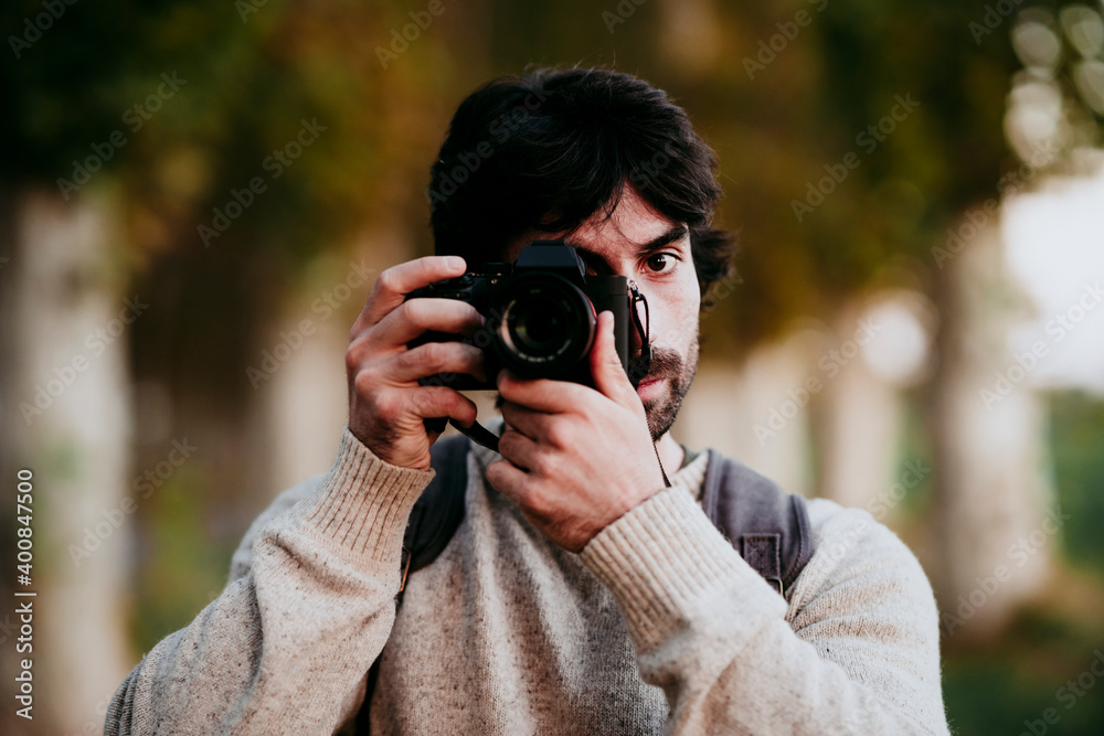 Mid adult man taking photo with camera while standing at forest Mid adult man taking photo with camera while standing at forest