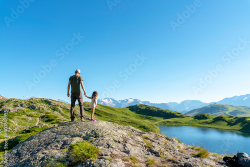 Father and daughter standing on rock object looking at view against clear sky photo