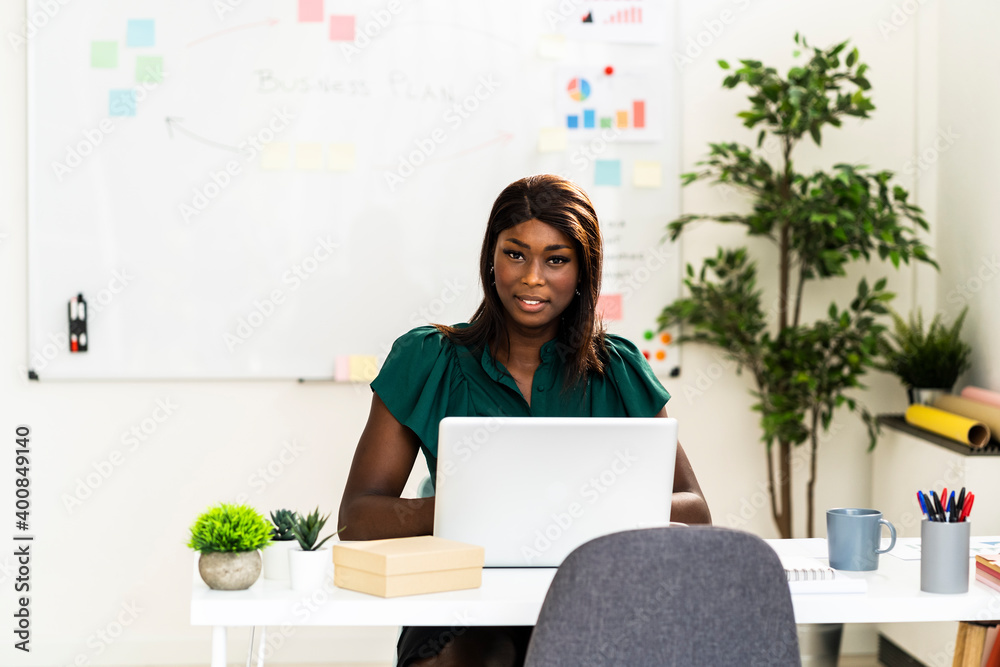 Businesswoman using laptop while sitting by desk at office Businesswoman using laptop while sitting by desk at office