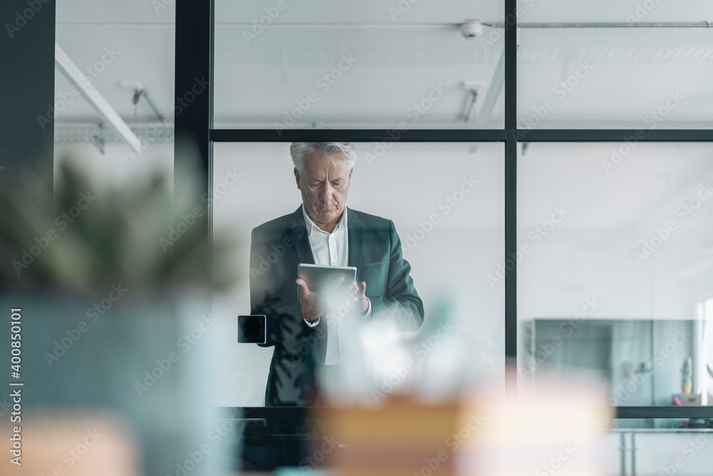 Businessman using digital tablet while standing at office Businessman using digital tablet while standing at office