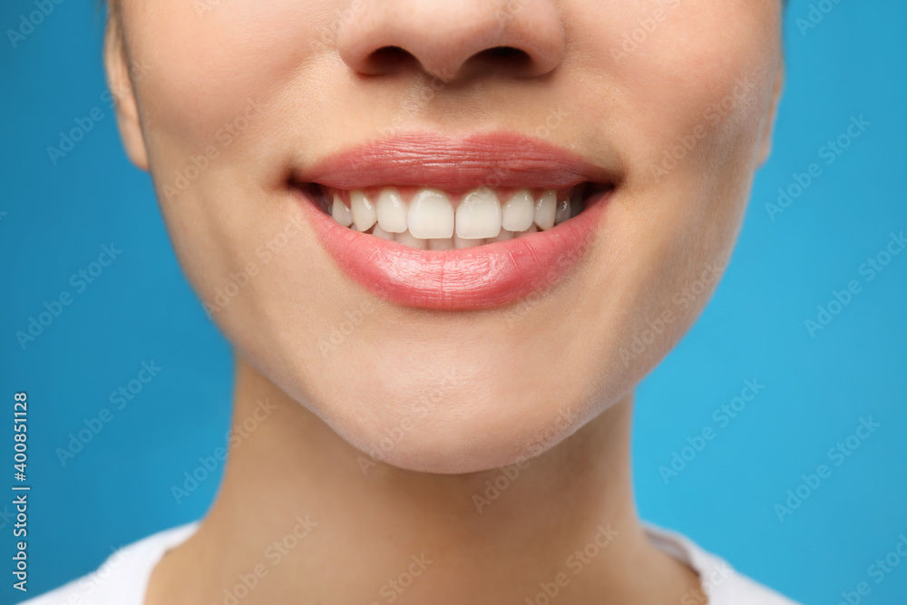 Obraz premium Woman with healthy teeth and beautiful smile on blue background, closeup. Cosmetic dentistry