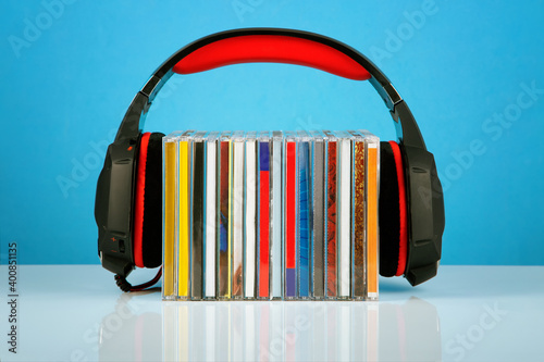 Headphones on a stack of CDs on a blue background.