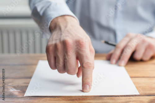 Index finger of a businessman on a white sheet of paper. In the office