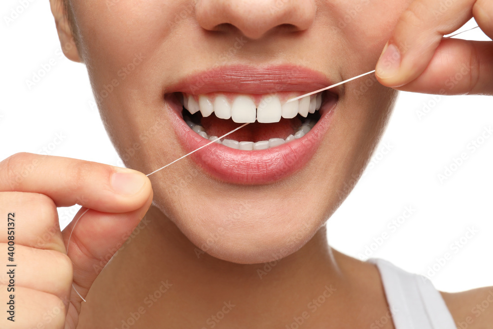 Obraz premium Young woman flossing her teeth on white background, closeup. Cosmetic dentistry