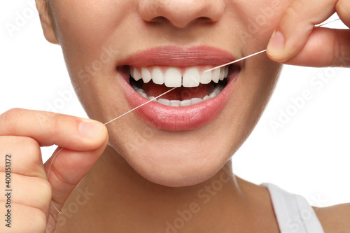 Young woman flossing her teeth on white background, closeup. Cosmetic dentistry