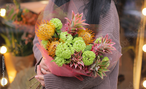 Flower shop. Beautiful bouquet of mixed exotic flowers in bright color in woman's hands. Work of the florist at a flower shop. Fresh cut flower.