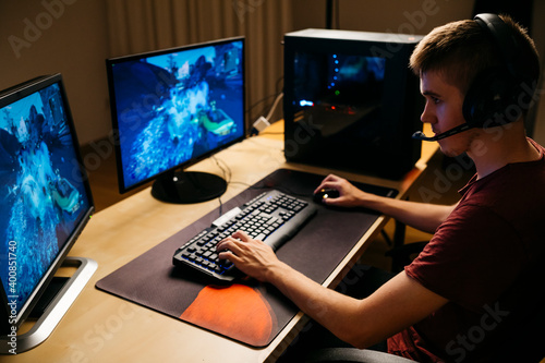 Young man playing video games with computer at desk photo