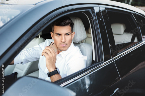 Handsome man with smartphone in modern car © New Africa