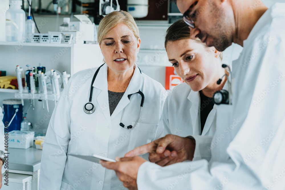 Male and female scientist using digital tablet while standing at laboratory Male and female scientist using digital tablet while standing at laboratory