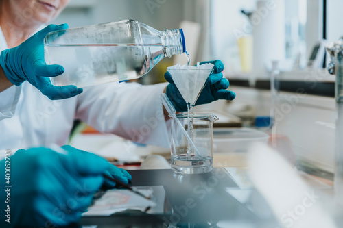 Scientist pouring filtering liquid while standing at laboratory photo