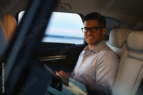 Handsome man using tablet on backseat of modern car © New Africa