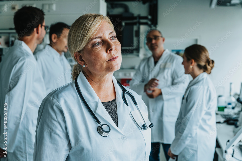 Female scientist looking away while standing with coworker in background at laboratory Female scientist looking away while standing with coworker in background at laboratory