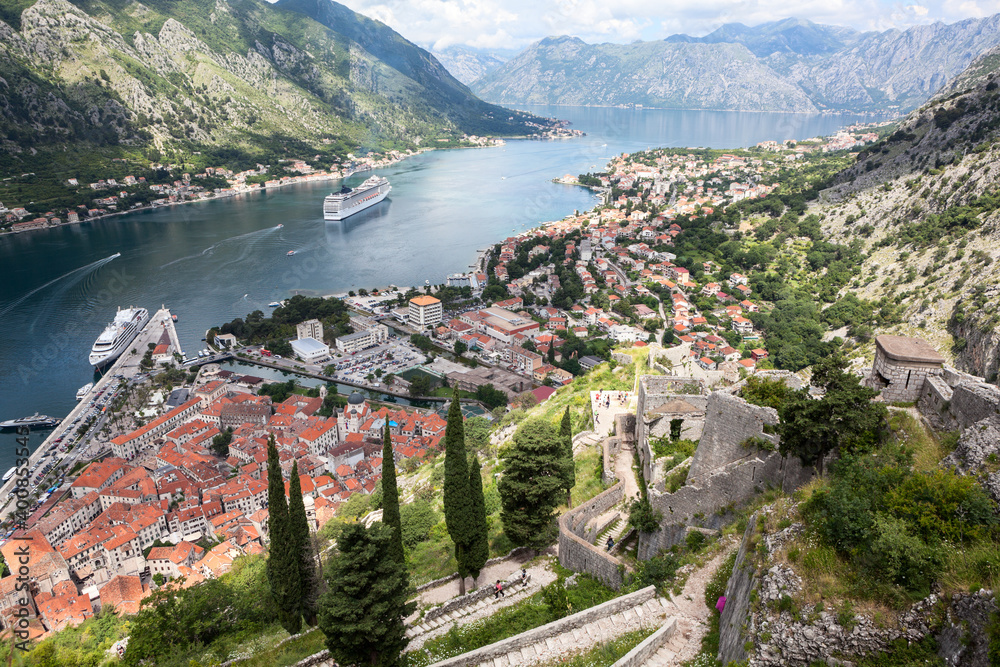 Panoramic view of the Kotor Gulf or Boka Kotorska with medieval town, sea port with ferryboats and surrounding mountains. View from the walls of fort. Montenegro, Europe