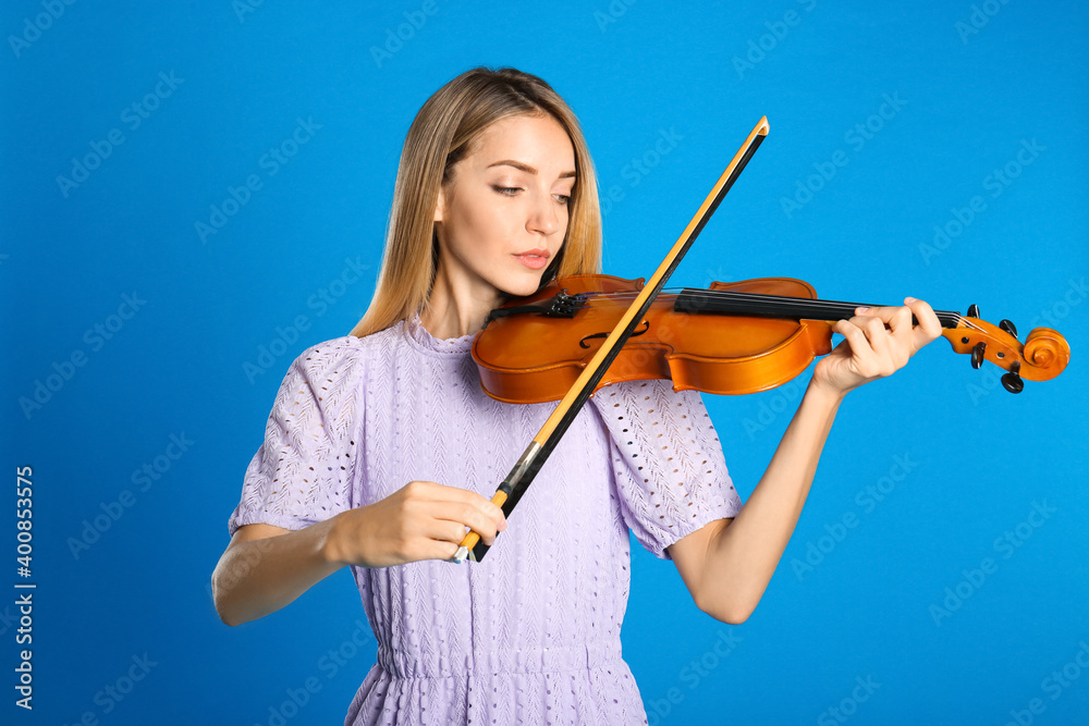 Beautiful woman playing violin on blue background Beautiful woman playing violin on blue background