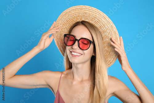 Beautiful woman in stylish sunglasses on light blue background
