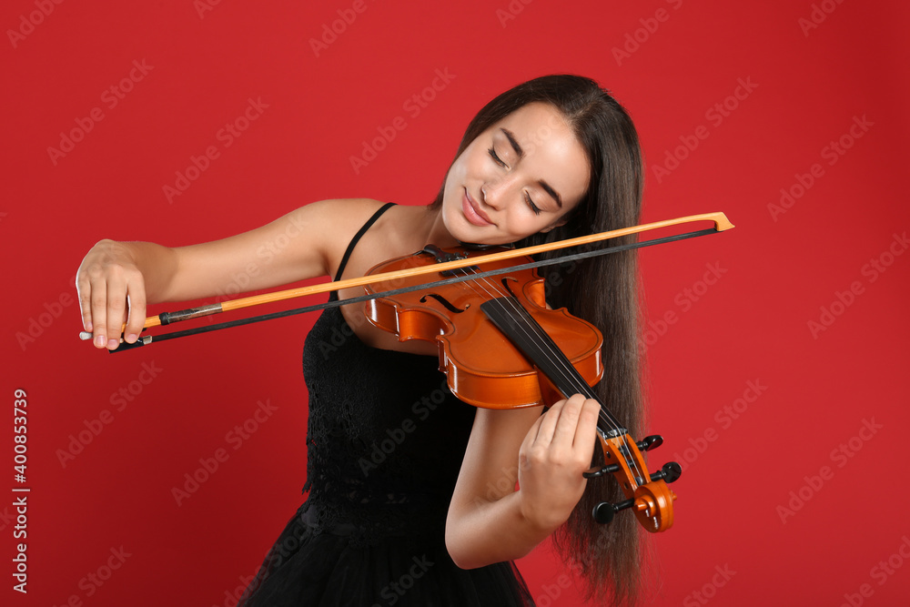 Beautiful woman playing violin on red background Beautiful woman playing violin on red background