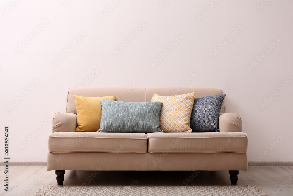 Comfortable beige sofa near light wall indoors, space for text. Simple interior - obrazy, fototapety, plakaty 
