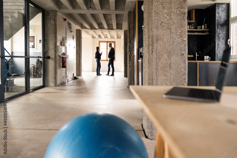 © Westend61 - Business people having conversation while standing against window at office © Westend61 - Business people having conversation while standing against window at office