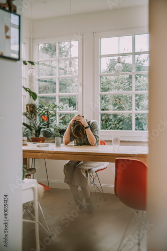 Depressed woman holding head while sitting at home