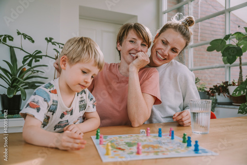 Mothers watching while son playing board game at home