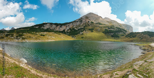 A panoramic view on the Le de Limo in Italian Dolomites. The lake has many shades, from turquoise to navy blue. High mountain behind it. High Alpine lake. Wandering and discovering remote places © Chris