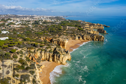 Portugal, Faro District, Albufeira, Drone view of Praia da Mare das Porcas, Praia da Coelha and surrounding cliffs with city in background photo