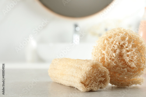 Natural loofah sponges on table in bathroom, closeup. Space for text photo