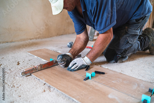 Male manual worker installing parquet flooring in house