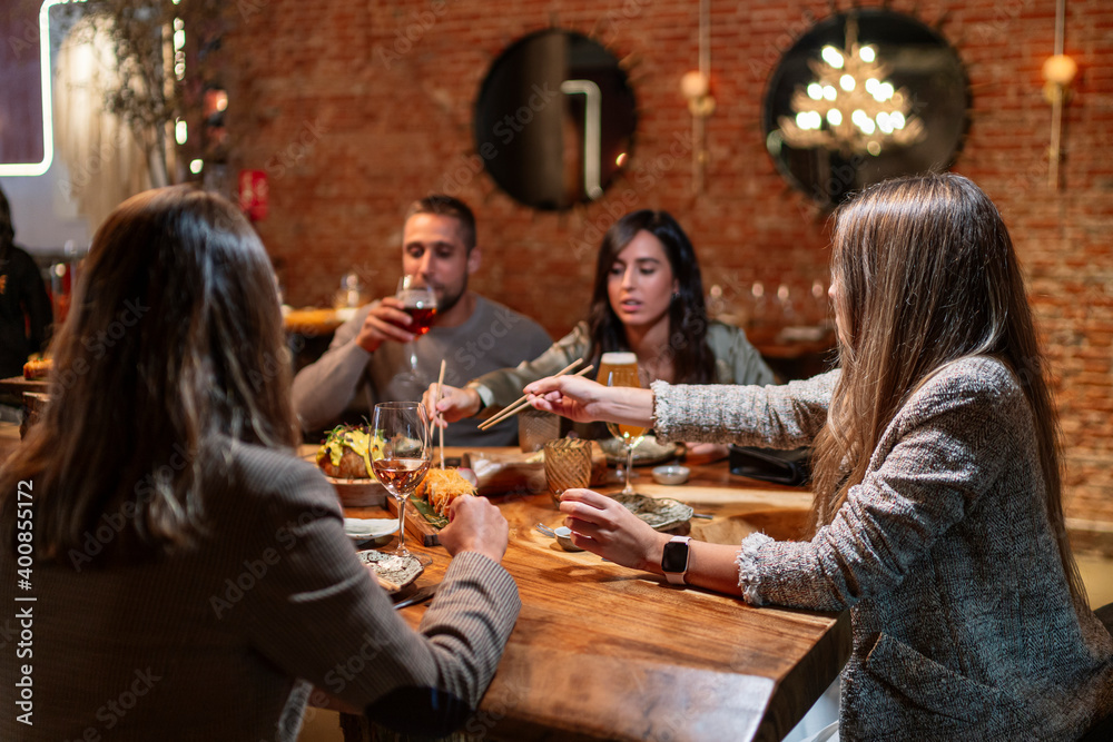 Friends having drink and food while sitting by table at restaurant Friends having drink and food while sitting by table at restaurant