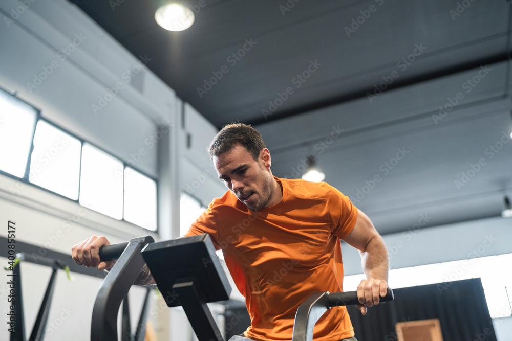 Male athlete exercising on exercise equipment in gym Male athlete exercising on exercise equipment in gym